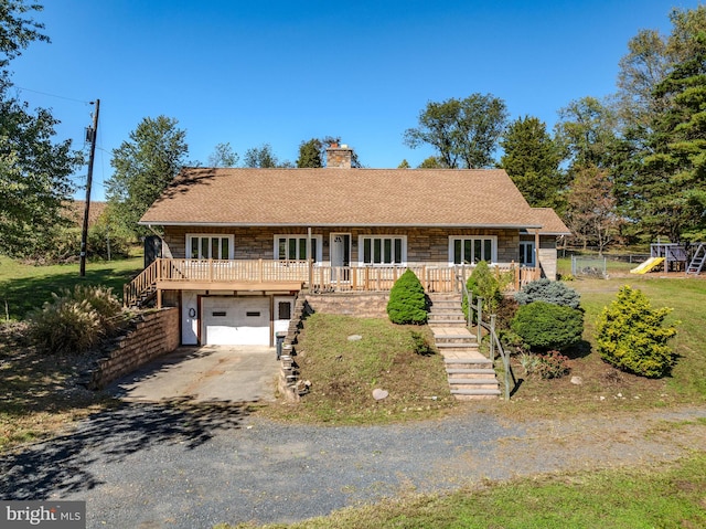 view of front facade featuring a playground, a garage, and covered porch