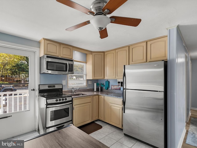 kitchen with light brown cabinetry, sink, stainless steel appliances, and light tile patterned floors