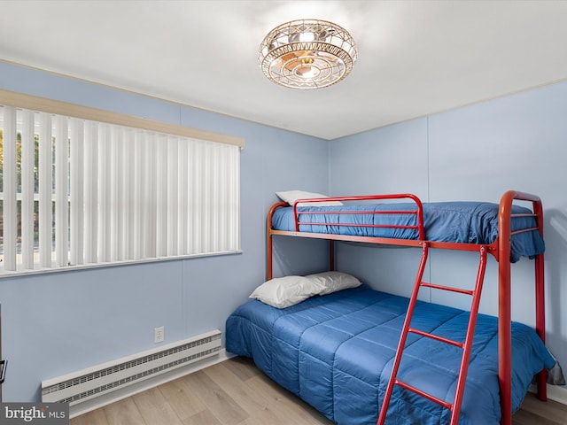 bedroom featuring a baseboard heating unit and hardwood / wood-style floors