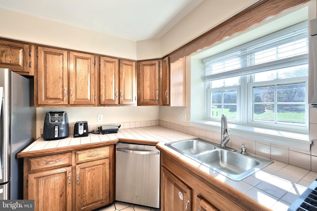 kitchen featuring appliances with stainless steel finishes, tile countertops, sink, and light tile patterned flooring