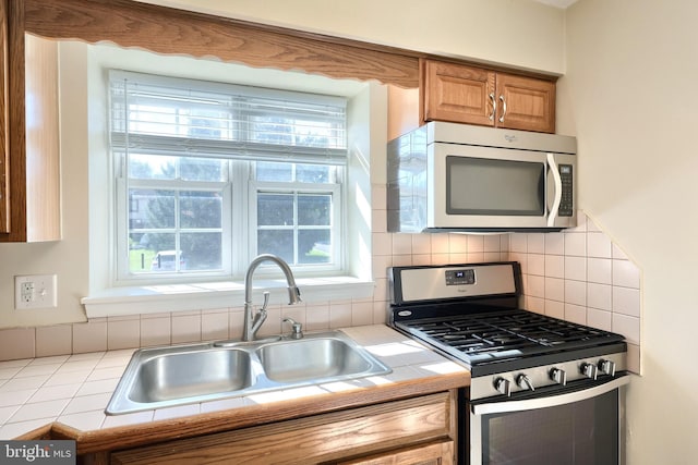 kitchen with plenty of natural light, appliances with stainless steel finishes, sink, and tile counters