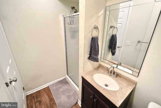 bathroom with vanity, hardwood / wood-style flooring, and a shower with door