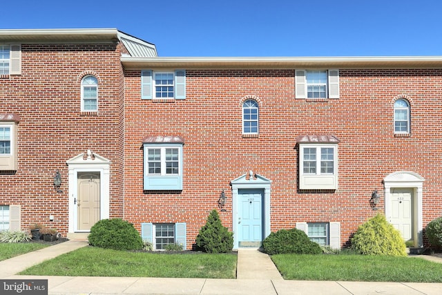 townhome / multi-family property featuring a front lawn