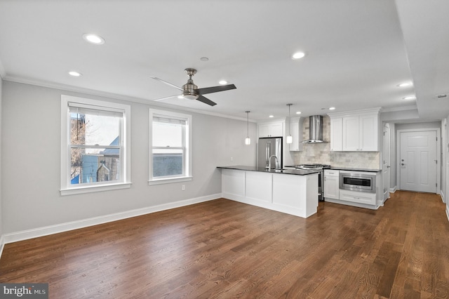 kitchen featuring pendant lighting, dark wood-type flooring, wall chimney range hood, white cabinetry, and stainless steel appliances