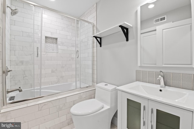 full bathroom with combined bath / shower with glass door, vanity, and toilet