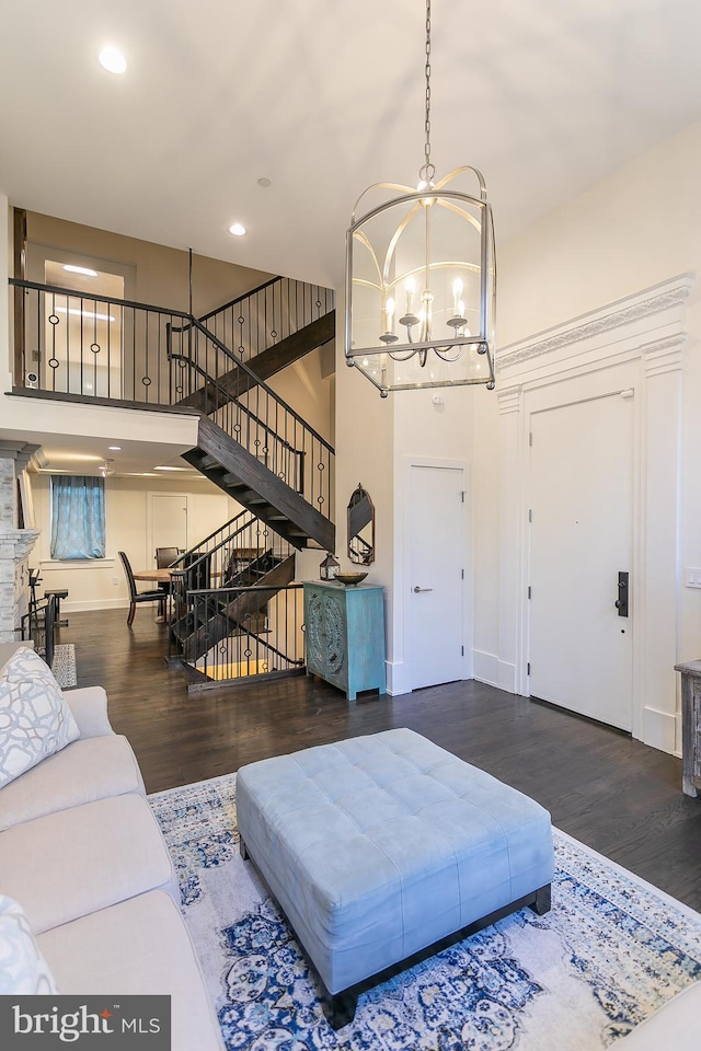 living room featuring a notable chandelier, a fireplace, a towering ceiling, and dark hardwood / wood-style flooring