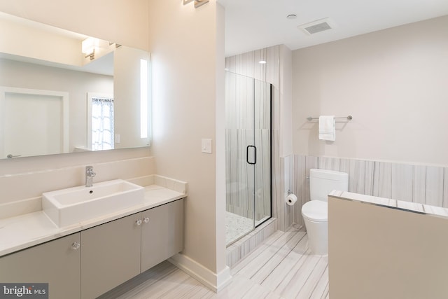 bathroom featuring toilet, a shower with shower door, and vanity