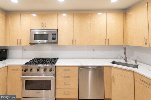 kitchen with light brown cabinets, light stone countertops, stainless steel appliances, and sink