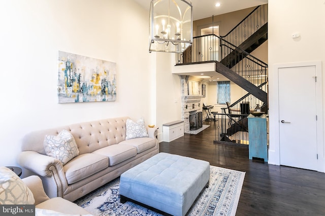 living room with dark wood-type flooring, a towering ceiling, and an inviting chandelier