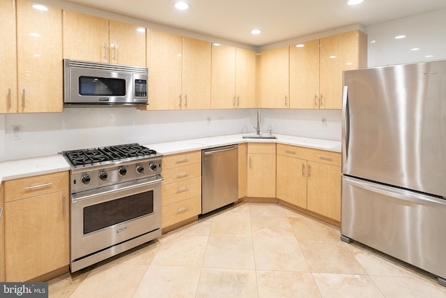 kitchen with light stone countertops, sink, light brown cabinetry, light tile patterned flooring, and stainless steel appliances