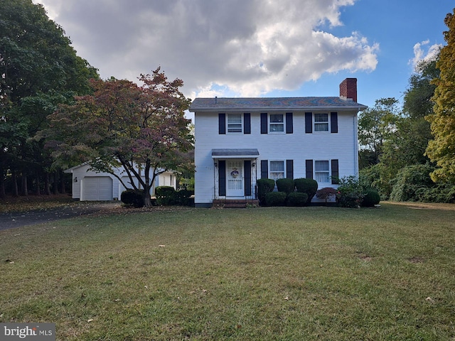 colonial house featuring a front lawn, an outbuilding, and a garage