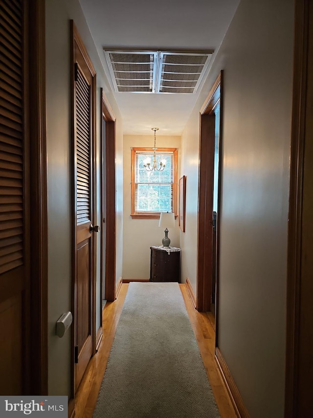 hallway featuring light hardwood / wood-style flooring and an inviting chandelier