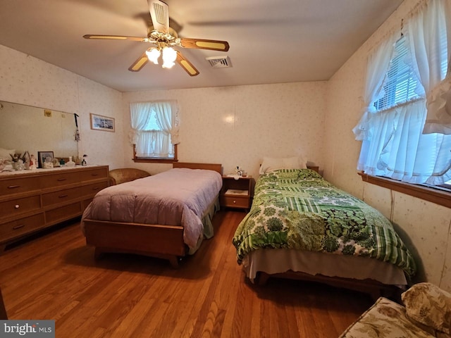 bedroom featuring multiple windows, wood-type flooring, and ceiling fan