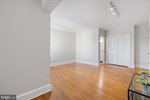 unfurnished room featuring track lighting and light hardwood / wood-style floors