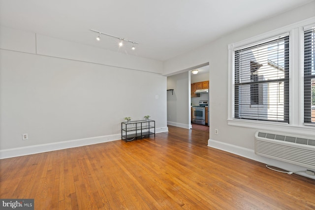 spare room featuring light wood-type flooring and a wall mounted air conditioner