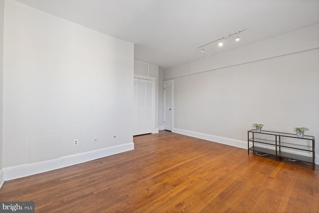 spare room featuring rail lighting and hardwood / wood-style floors