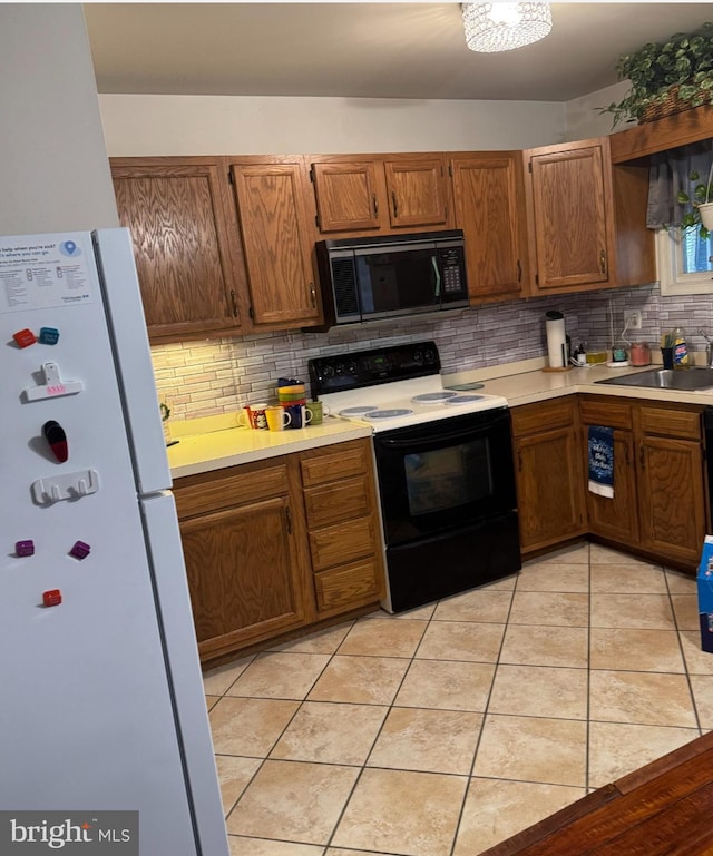 kitchen with sink, tasteful backsplash, black appliances, and light tile patterned flooring