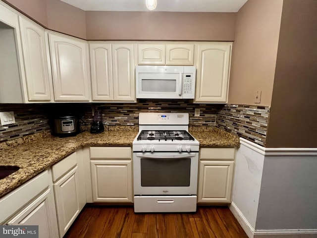 kitchen with white cabinets, dark stone countertops, white appliances, and dark wood-type flooring