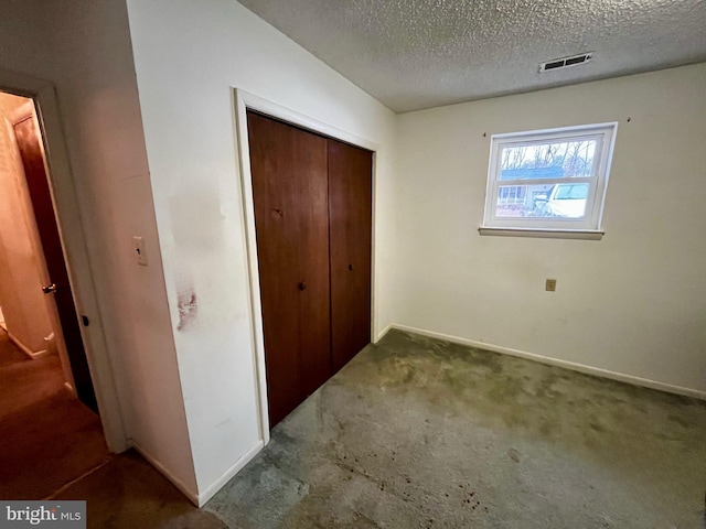 unfurnished bedroom featuring a textured ceiling, a closet, and carpet