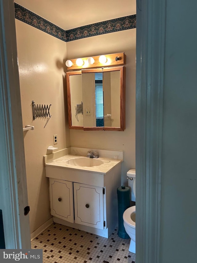 bathroom with toilet, vanity, and tile patterned floors