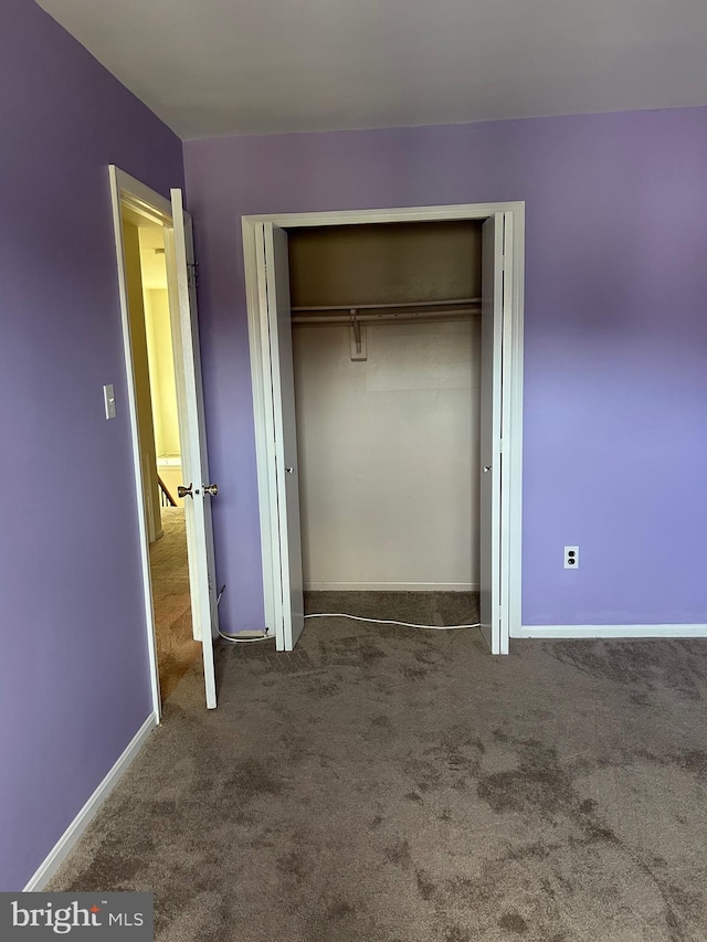 unfurnished bedroom with a closet and dark carpet