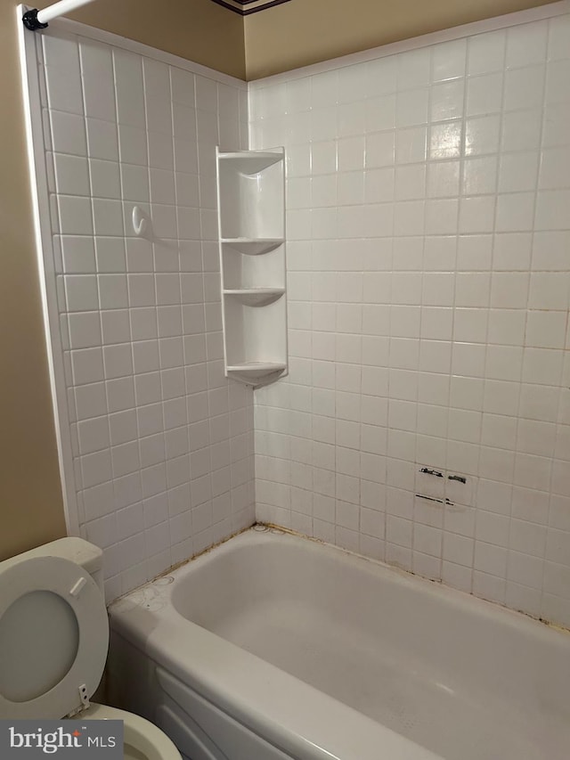 bathroom featuring toilet and tiled shower / bath