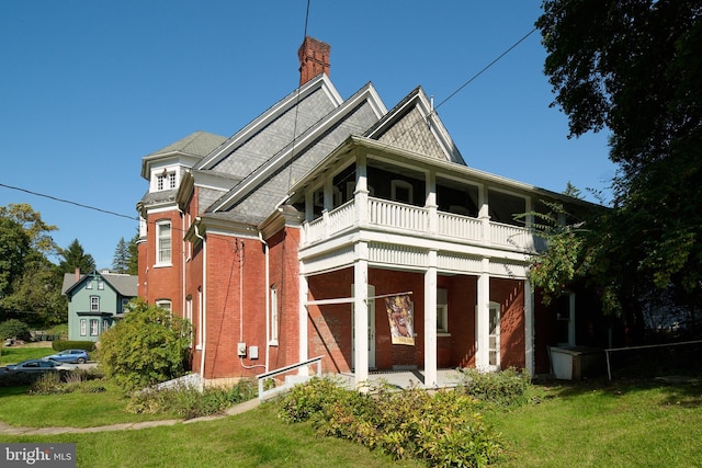 rear view of property featuring a balcony and a lawn