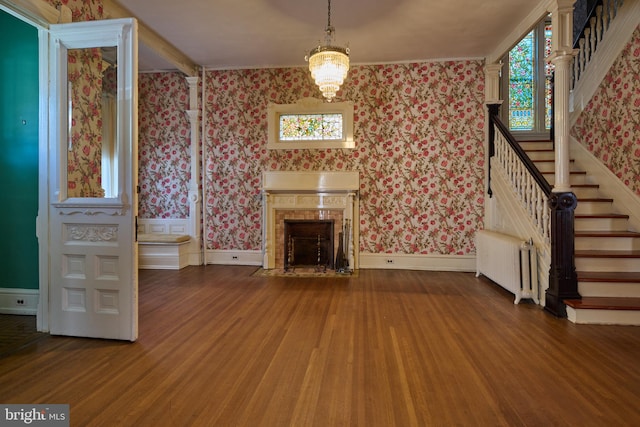 unfurnished living room with hardwood / wood-style flooring, a notable chandelier, and radiator heating unit