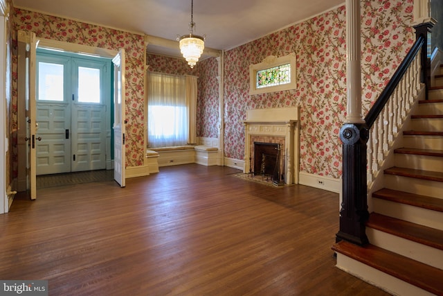 unfurnished living room featuring a notable chandelier, dark hardwood / wood-style flooring, and a tile fireplace