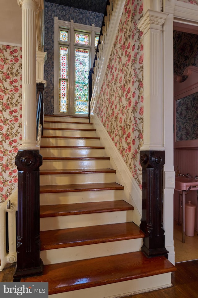 stairway featuring decorative columns and hardwood / wood-style flooring