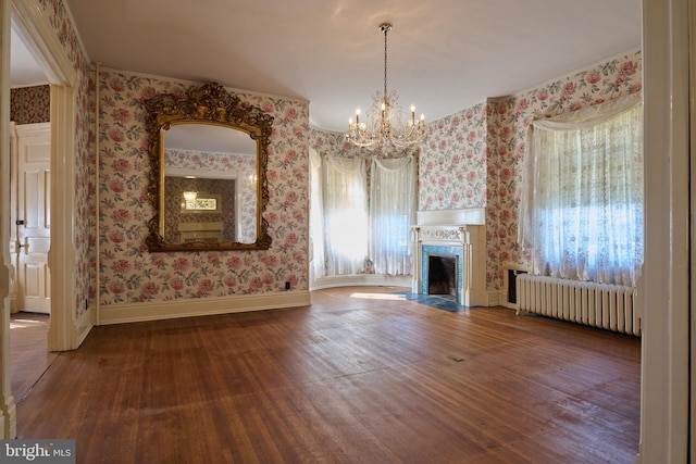 unfurnished living room with hardwood / wood-style floors, radiator heating unit, and a notable chandelier