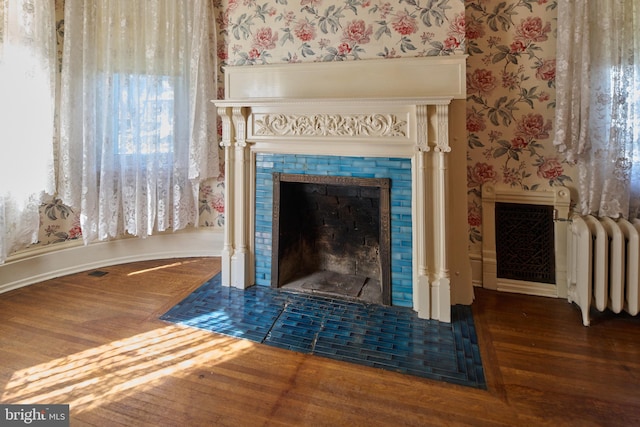 interior details featuring a tile fireplace, radiator, and hardwood / wood-style flooring