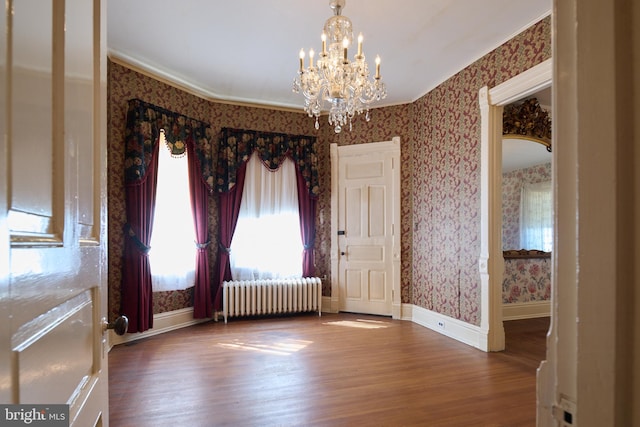 interior space with wood-type flooring, radiator, crown molding, and a chandelier