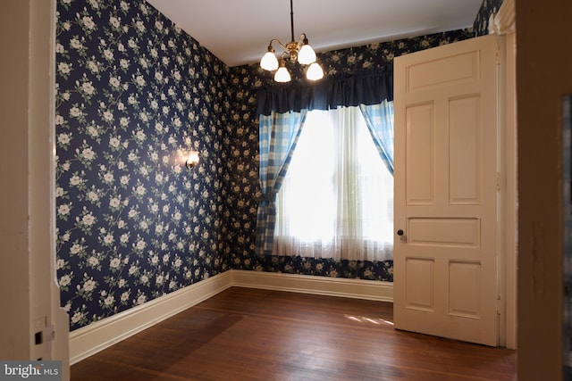 spare room with dark hardwood / wood-style flooring and a chandelier