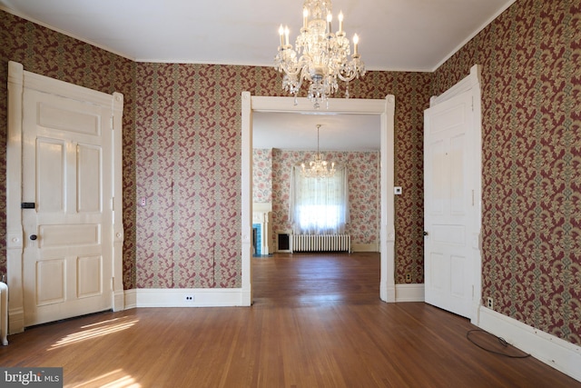 unfurnished dining area with crown molding, radiator, dark hardwood / wood-style floors, and a chandelier