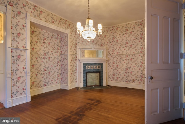 unfurnished living room featuring crown molding, a tiled fireplace, dark hardwood / wood-style flooring, and a chandelier