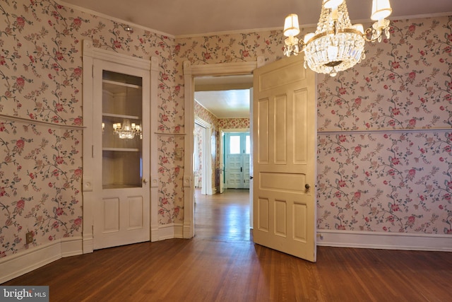 unfurnished dining area with an inviting chandelier, dark hardwood / wood-style floors, and crown molding