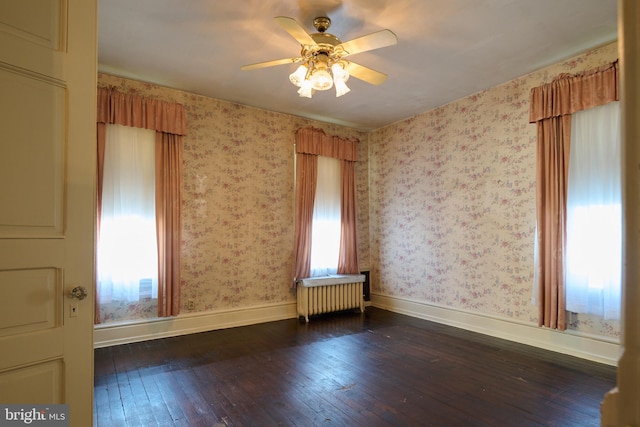 empty room featuring radiator heating unit, ceiling fan, and dark hardwood / wood-style flooring