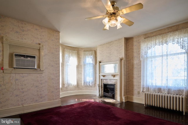 unfurnished living room with radiator heating unit, ceiling fan, hardwood / wood-style flooring, and a wall mounted AC