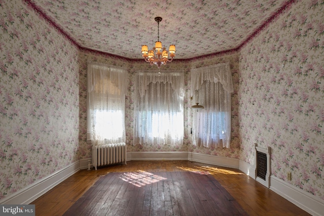 unfurnished dining area featuring an inviting chandelier, crown molding, hardwood / wood-style floors, and radiator heating unit