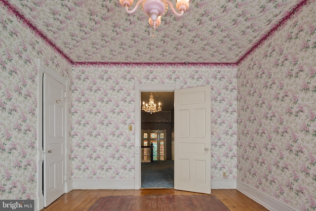 unfurnished room with wood-type flooring and a notable chandelier