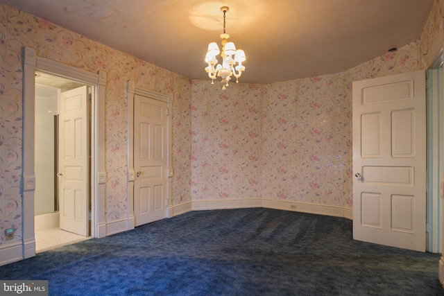 carpeted spare room with an inviting chandelier