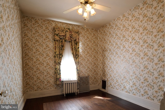 unfurnished room featuring ceiling fan, dark wood-type flooring, and radiator heating unit