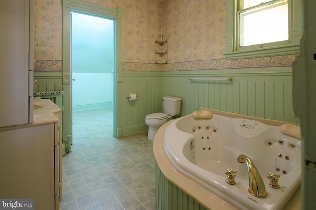 bathroom with vanity, a tub to relax in, and toilet