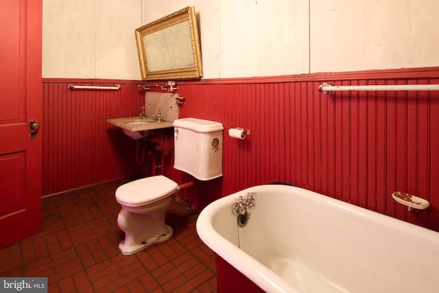 130 E Linn St, Bellefonte, PA 16823 - bathroom with toilet, a freestanding bath, wainscoting, and brick floor