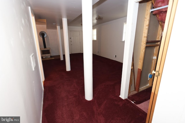 basement with dark carpet and a wood stove