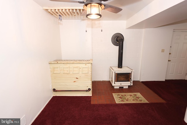 interior details featuring ceiling fan and a wood stove