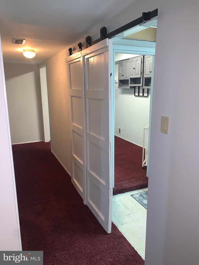 corridor featuring a barn door and carpet