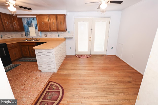 kitchen with sink, decorative backsplash, light hardwood / wood-style floors, crown molding, and french doors