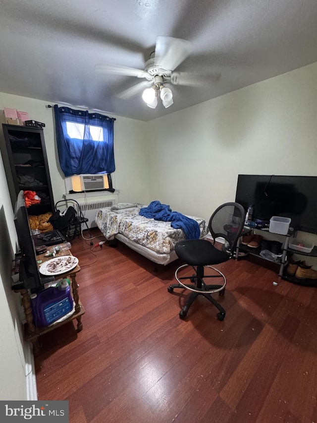 bedroom with radiator heating unit, ceiling fan, and hardwood / wood-style floors